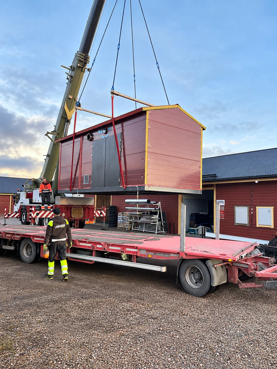 A red heating plant being lifted by crane from a trailer