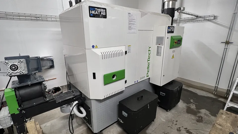 The PelleTech IDRO 300 in the boiler room, with the rotary valve on the left.