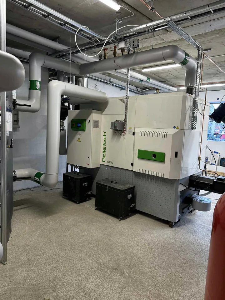 The boiler room, with the PelleTech IDRO 500 and two ash boxes on wheels.