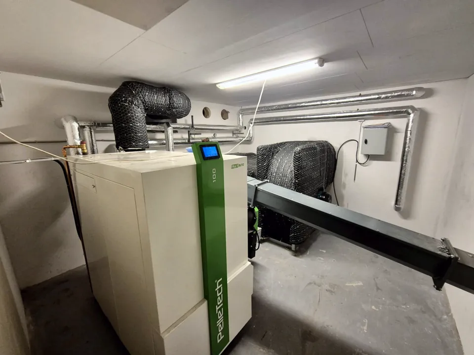 The PelleTech Multiauto 100 in the boiler room, with the feed screw from the store.